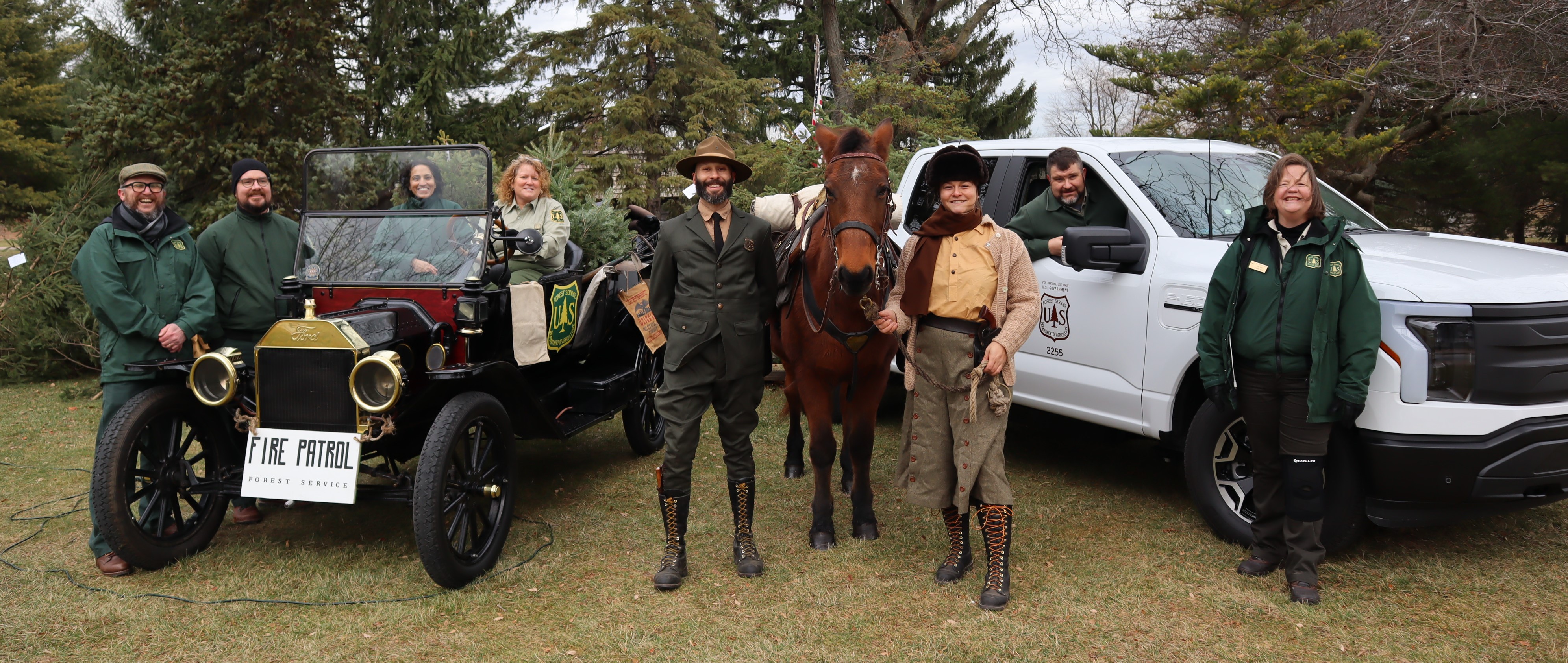 United States Forest Service employees stand with an old car, horse, and truck.