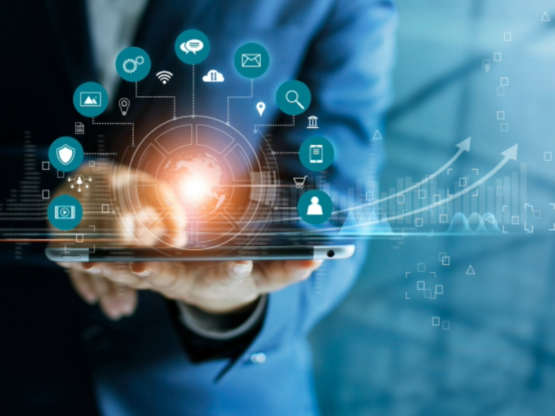 A business person holding an iPad with imagery of technology icons overlaping the device.
