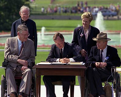 President George H.W. Bush signing Americans with Disabilities Act of 1990 on the South Lawn of the White House. L to R, sitting: Evan Kemp, Chairman, Equal Employment Opportunity Commission, Justin Dart, Chairman, President's Committee on Employment of People with Disabilities. L to R, standing: Rev. Harold Wilke and Swift Parrino, Chairperson, National Council on Disability, 07/26/1990