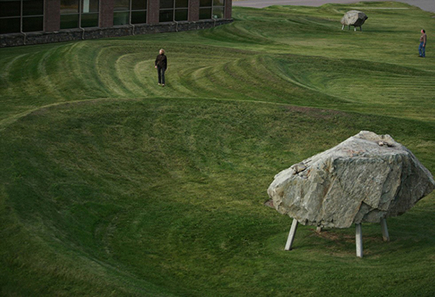 A field of smoothly tapered earth mounds and a series of irregularly spaced boulders.