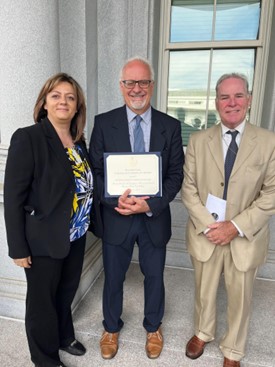 three people stand together holding a certificate