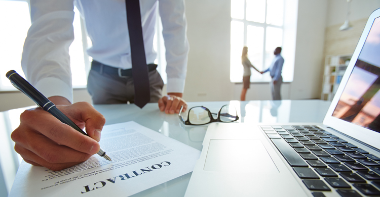 Person in a tie signing a paper contract