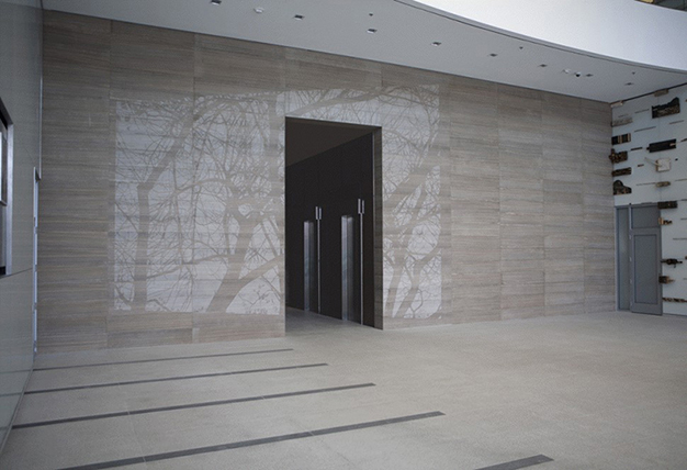 Image of sunlight dappling through tree branches by subtly etching their silhouettes into the wall’s polished limestone surface