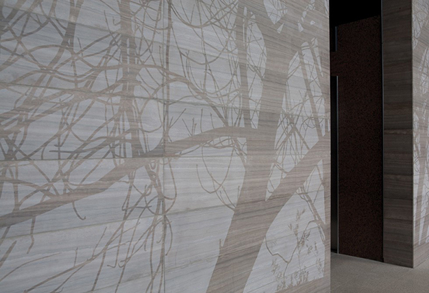 Image of sunlight dappling through tree branches by subtly etching their silhouettes into the wall’s polished limestone surface