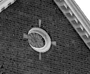 exterior of a building showing a round, bull's eye, window in the gable