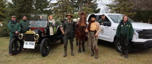 United States Forest Service employees stand with an old car, horse, and truck.