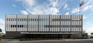 a white building with two rows of windows and an America flag flying next to it