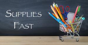 A tiny cart with pencils and school supplies in front of a chalkboard that says Supplies Fast