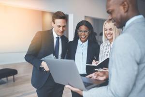 Business people surround a laptop in a meeting