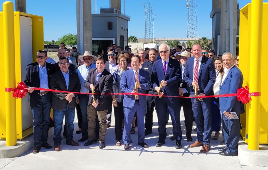 A group of individuals smile as they cut the red ribbon.