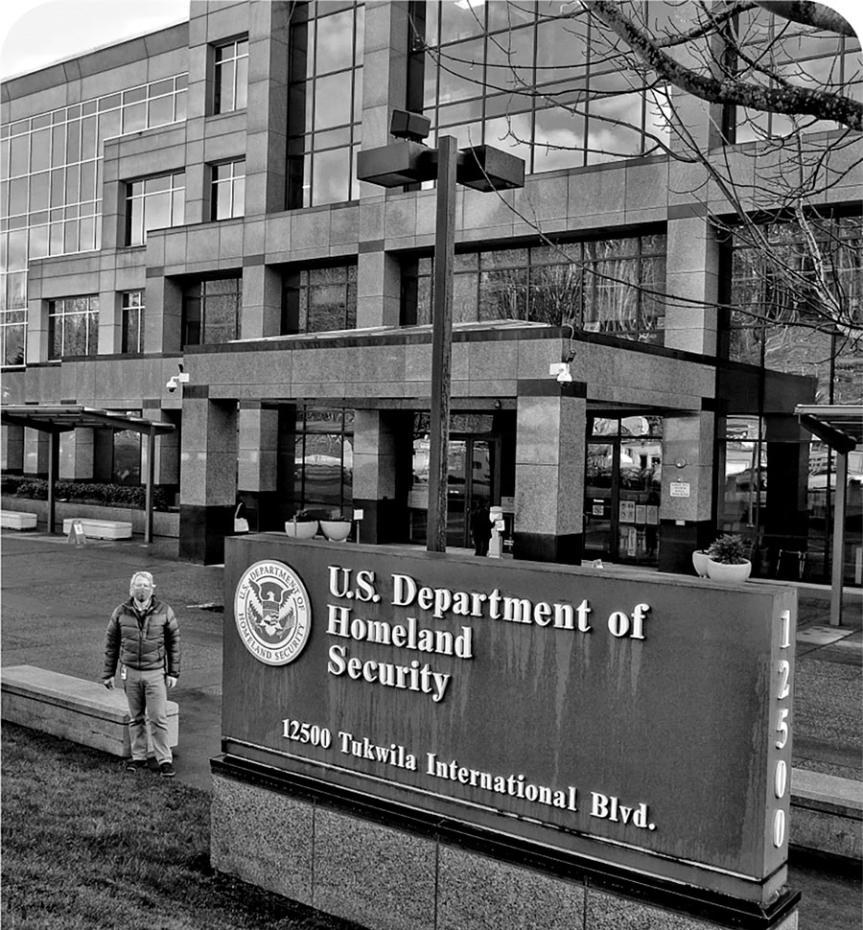 A man in a puffer jacket and facemask standing in front of a stone and glass building