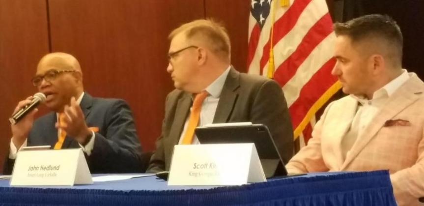 Medium shot of three panelists with one speaking with mic