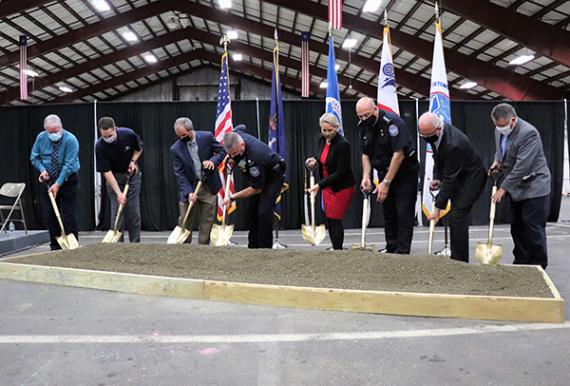 people stand in front of dirt holding shovels