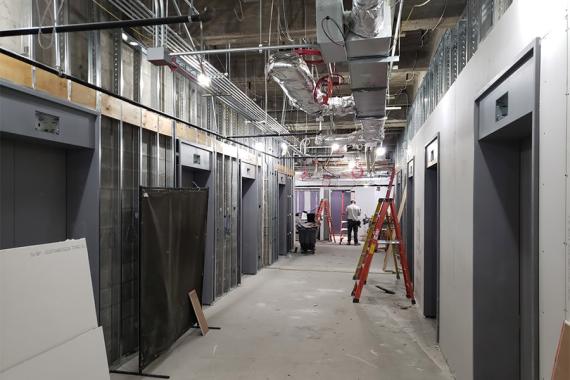 A hallway under construction with elevator doors along both sides