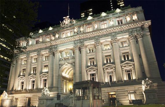 Front view of a light stone multi-story ornate building with columns