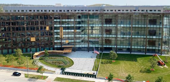 A multi-story glass front building with 5 wooden patches over windows and a wooden roof over a pedestrian pathway.