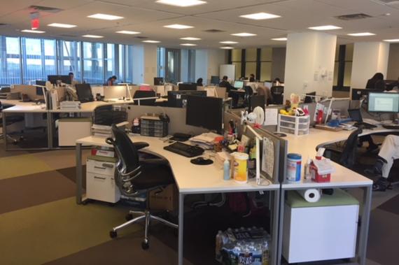 Photo of an open office at GSA headquarters, full of people, equipment, and personal effects