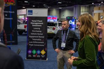 A woman smiling and talking with people at a car show