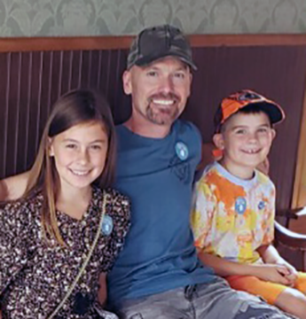 Three people smiling while seated on a bench indoors.