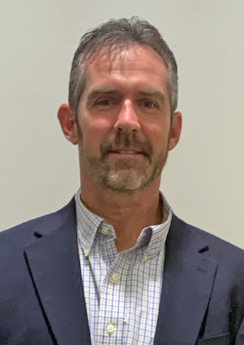 Person in business shirt and sports jacket with a slight smile.