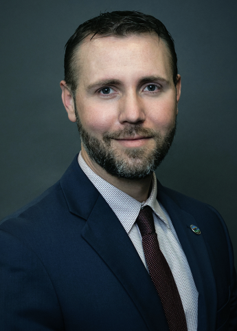 Person in suit and tie with dark background.