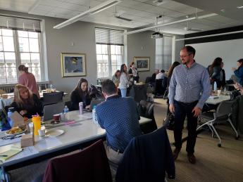 several employees working at tables and one employee standing and talking