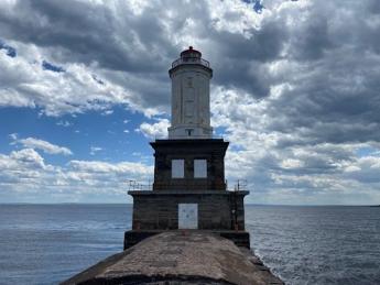 A white lighthouse with a brick base on the edge of the water