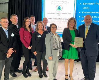 Group of people in business attire standing in front of screen accepting plaque award