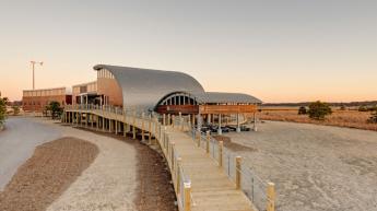 Chesapeake Bay Brook Environmental Center. A modern, two-story building with a curved metal roof, which sits on pillars above ground.