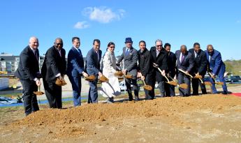Twelve people in business attire standing on dirt