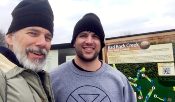A person in front of a sign that reads: Bad Rock Creek Disc Golf Course