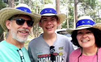 Three people pose for a photo outdoors.