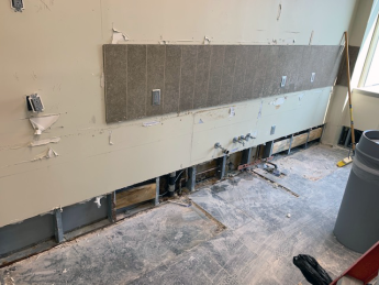 Photo of office space with carpets, panels and about two feet of the bottom of a wall removed.