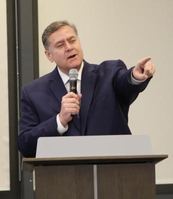 Michael Copeland standing behind a podium in GSA's conference center pointing.