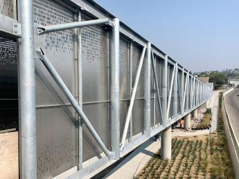 Partial angle view of a silver pedestrian bridge next to a road