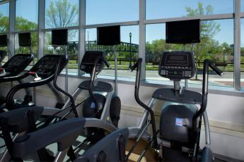 Photo of a fitness center in an office building with exercise equipment facing a window