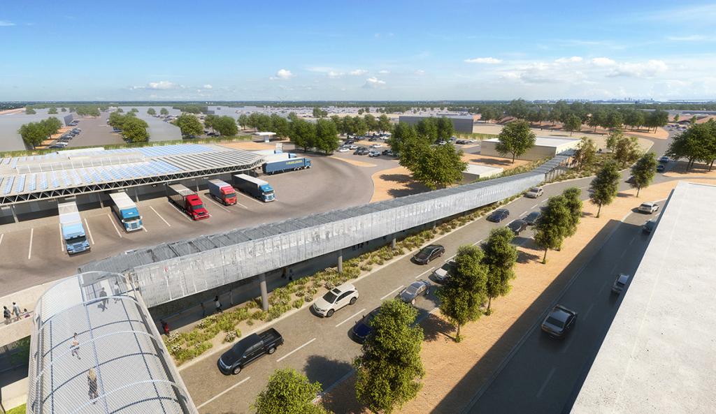 A pedestrian bridge over a street, with a parking lot with four trucks on the far side
