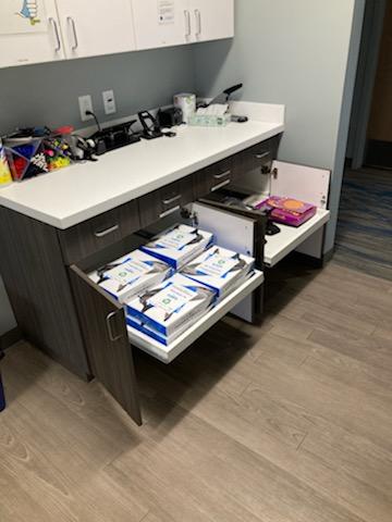 Supply room cabinets with slide out drawers holding unused printing paper and other larger supply items.