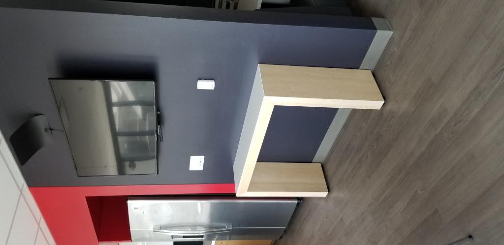 A narrow wooden table placed under a wall-mounted television in a break room area.